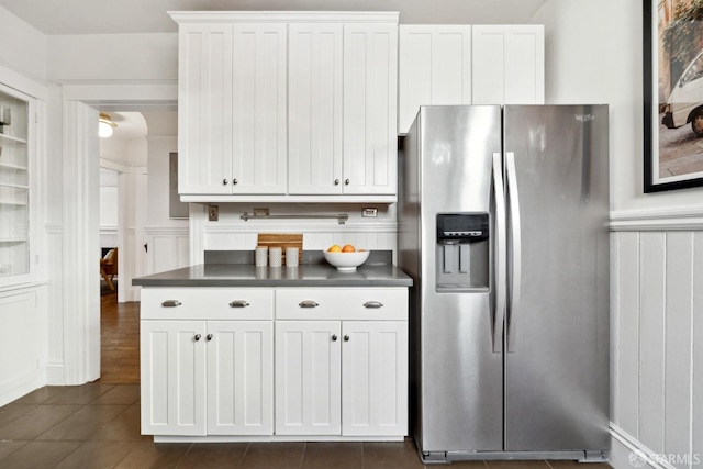 kitchen with stainless steel refrigerator with ice dispenser, dark tile patterned floors, and white cabinetry