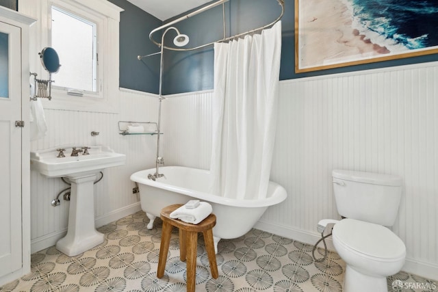 bathroom with sink, wood walls, and toilet