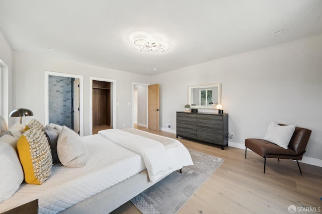 bedroom with a spacious closet, light hardwood / wood-style floors, and a closet