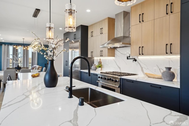 kitchen featuring high end appliances, light stone countertops, light brown cabinets, and wall chimney range hood