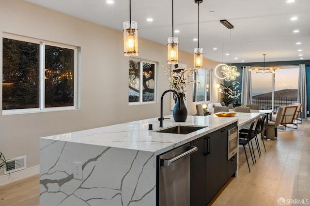 kitchen featuring hanging light fixtures, light stone countertops, sink, and appliances with stainless steel finishes