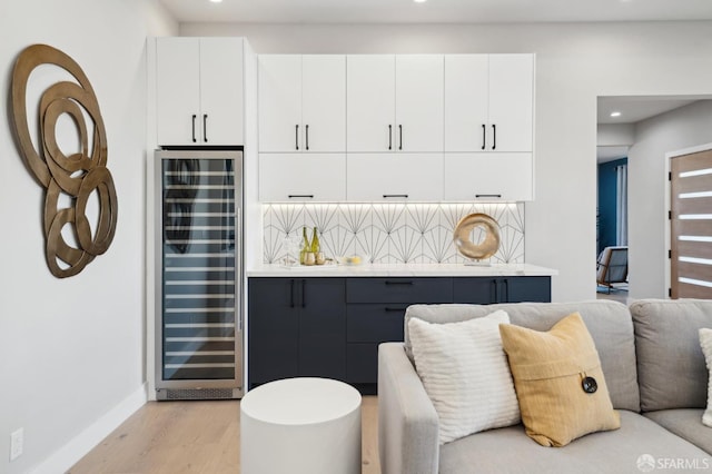 interior space with indoor bar, wine cooler, and light hardwood / wood-style flooring