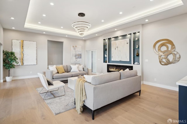 living room featuring light hardwood / wood-style floors and a tray ceiling