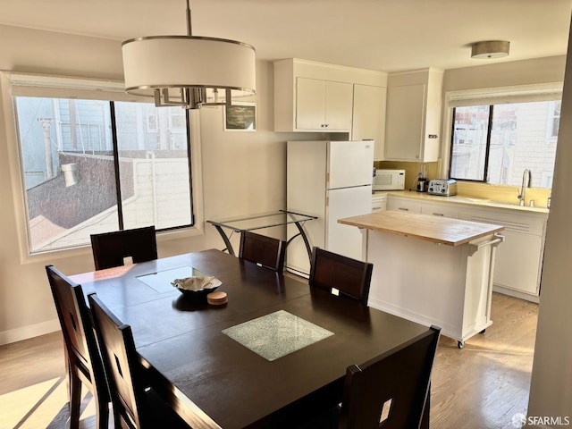 dining space featuring a toaster, light wood-style flooring, and baseboards