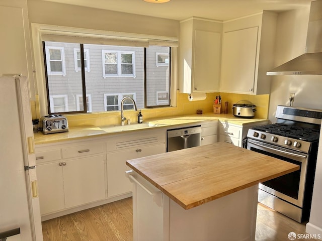 kitchen featuring stainless steel appliances, wooden counters, wall chimney exhaust hood, and tasteful backsplash