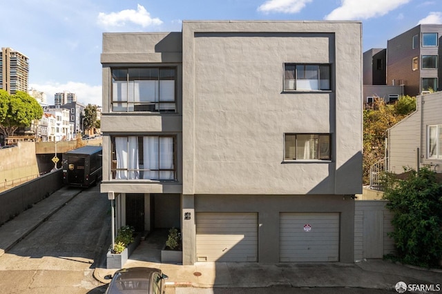 view of front facade with driveway, an attached garage, and stucco siding