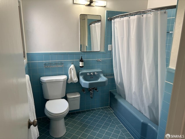 bathroom with toilet, tile walls, a sink, and tile patterned floors