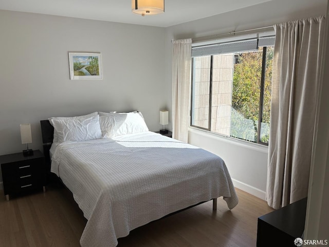 bedroom featuring multiple windows, baseboards, and wood finished floors