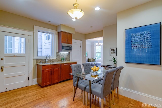 kitchen featuring light hardwood / wood-style floors, stainless steel microwave, sink, and pendant lighting