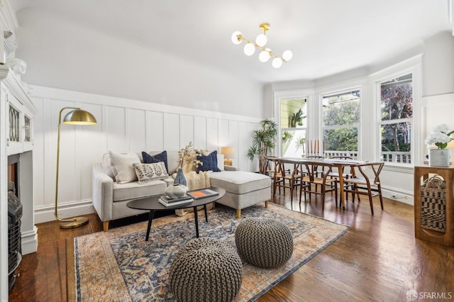 living room featuring a wainscoted wall, a decorative wall, wood finished floors, and a notable chandelier