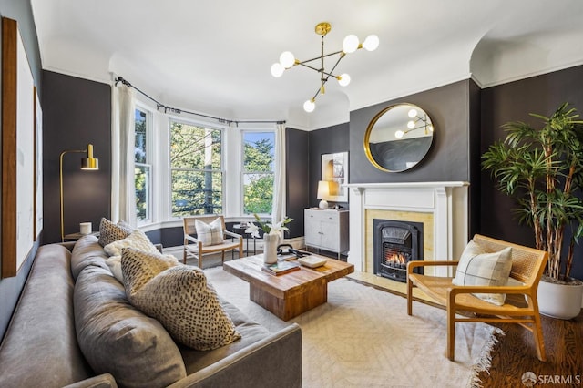 living room featuring ornamental molding, a notable chandelier, and a high end fireplace