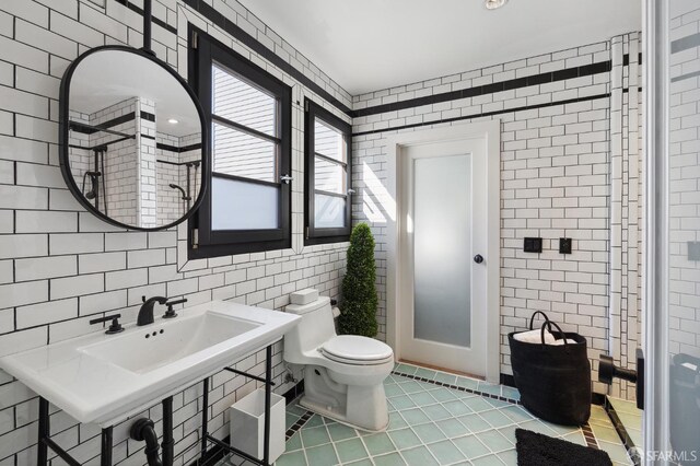 bathroom featuring tile walls, tile patterned flooring, toilet, and sink