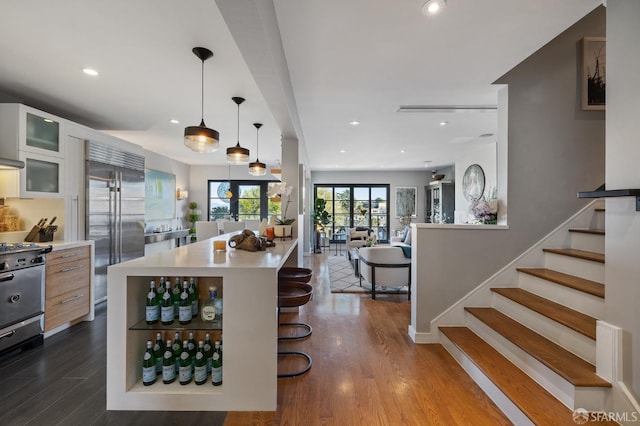 kitchen with a kitchen bar, appliances with stainless steel finishes, dark wood-type flooring, and a kitchen island