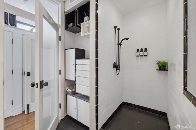 bathroom with a tile shower and hardwood / wood-style flooring