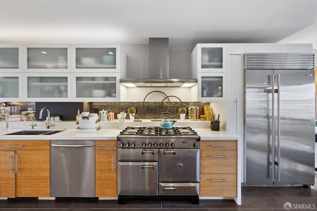 kitchen with decorative backsplash, dark wood-type flooring, wall chimney exhaust hood, premium appliances, and sink