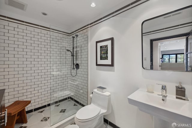 bathroom with tiled shower, sink, tile patterned floors, and toilet