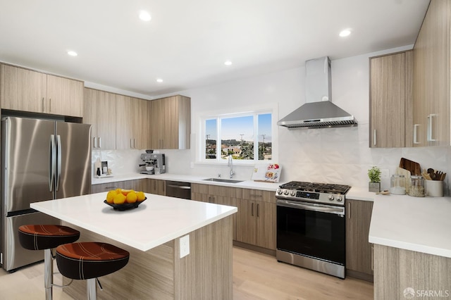 269 E Ave, San Bruno, CA 94066 - kitchen featuring stainless steel appliances, wall chimney range hood, a kitchen breakfast bar, light wood-type flooring, and light countertops