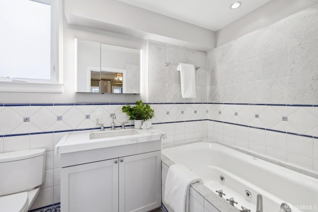 full bath featuring a jetted tub, toilet, tile walls, and vanity