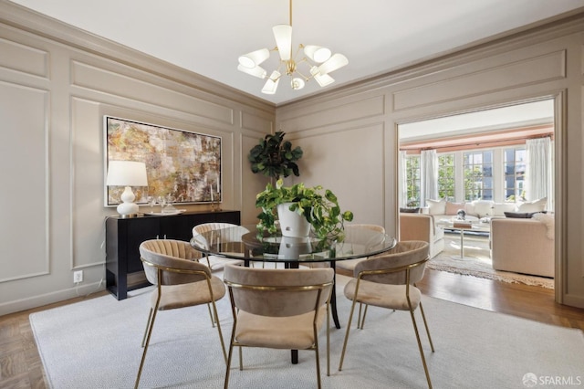 dining space featuring a chandelier, ornamental molding, and a decorative wall