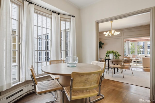 dining space featuring a baseboard heating unit, ornamental molding, dark wood finished floors, and a notable chandelier