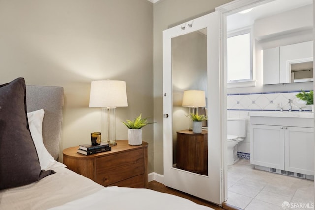 bedroom featuring light tile patterned floors, a sink, and ensuite bathroom