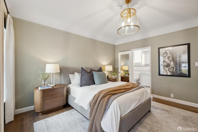 bedroom featuring dark wood-style floors, a chandelier, ensuite bath, and baseboards