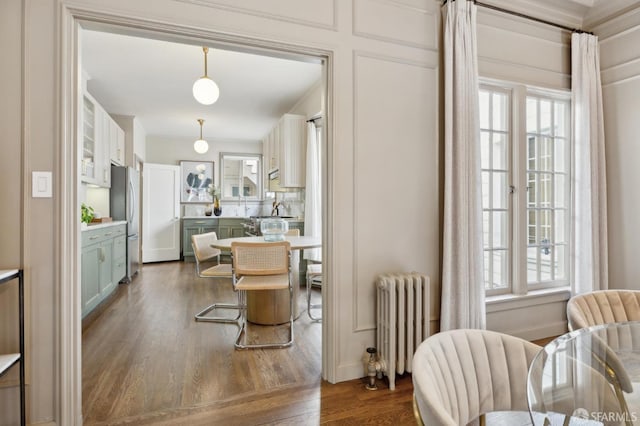 dining area with dark wood-type flooring and radiator