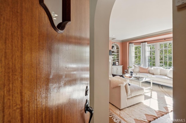 living room featuring built in shelves, arched walkways, and crown molding