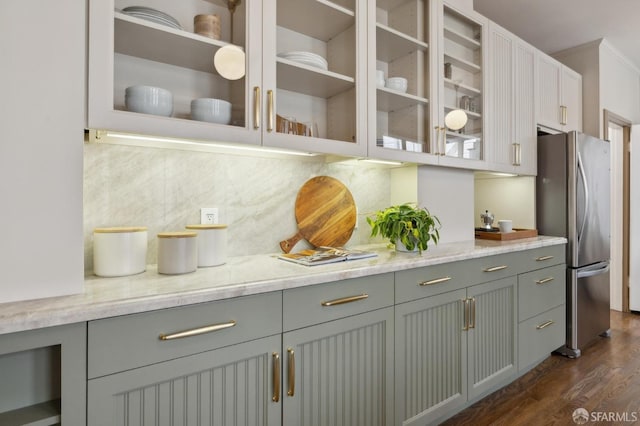 bar featuring dark wood-style floors, freestanding refrigerator, and decorative backsplash