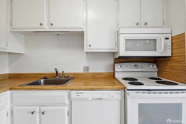 kitchen with white appliances, sink, and white cabinets