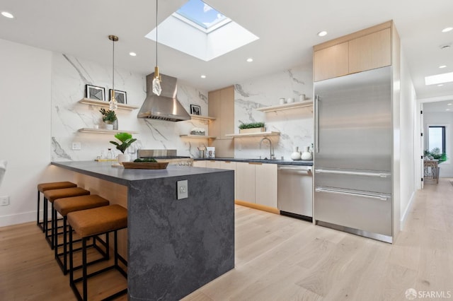 2287 45th Ave, San Francisco, CA 94116 - kitchen featuring open shelves, appliances with stainless steel finishes, wall chimney range hood, dark countertops, and a kitchen bar