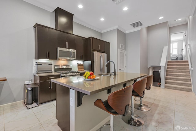 kitchen featuring a breakfast bar, crown molding, dark brown cabinets, a center island with sink, and stainless steel appliances