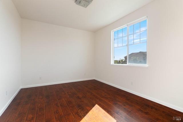 spare room with baseboards and dark wood finished floors