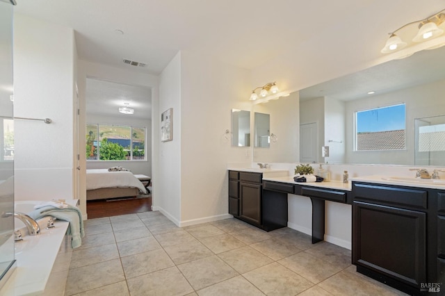 ensuite bathroom with a sink, tile patterned floors, a wealth of natural light, and visible vents