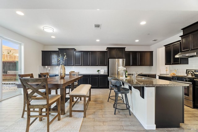 kitchen featuring a sink, stainless steel appliances, tasteful backsplash, under cabinet range hood, and visible vents