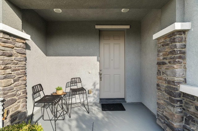 entrance to property with stone siding and stucco siding