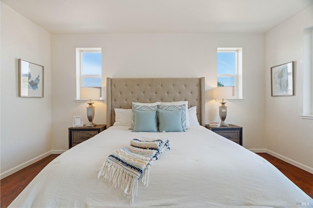 bedroom featuring baseboards, dark wood finished floors, and multiple windows