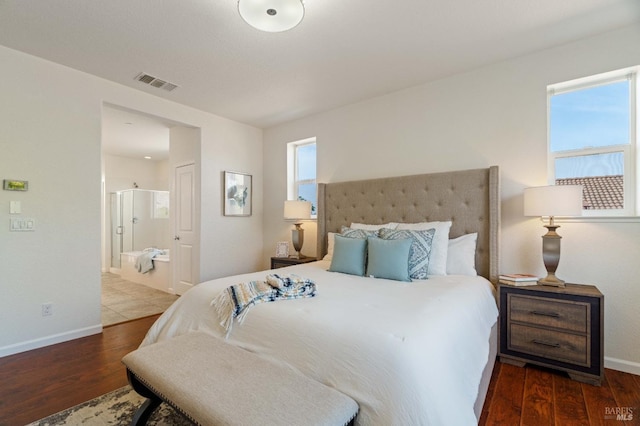 bedroom featuring baseboards, visible vents, wood finished floors, and ensuite bath