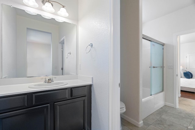 ensuite bathroom with vanity, toilet, tile patterned floors, enclosed tub / shower combo, and baseboards