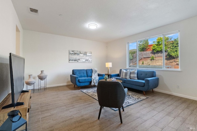 living area featuring baseboards, visible vents, and wood finished floors