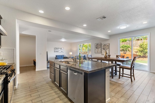 kitchen featuring visible vents, a sink, open floor plan, light wood-style floors, and stainless steel appliances