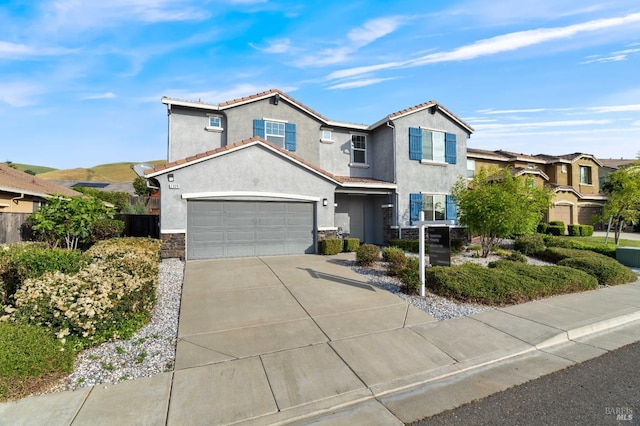 traditional-style home with stone siding, stucco siding, a tiled roof, concrete driveway, and an attached garage