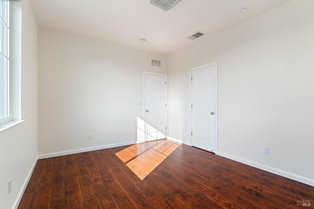 unfurnished room with baseboards, hardwood / wood-style floors, and visible vents