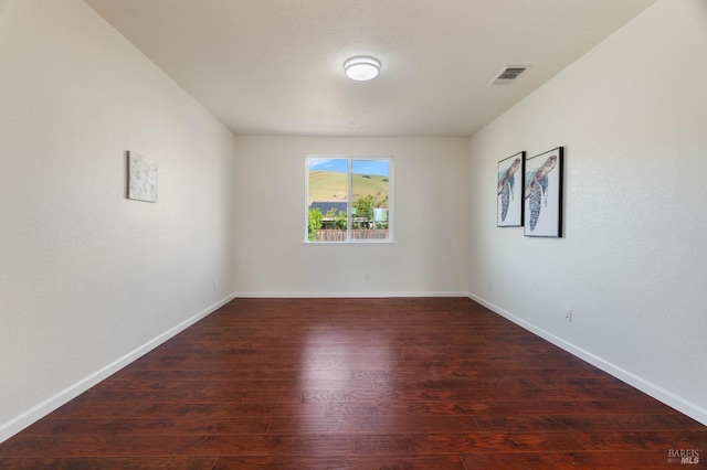 spare room with visible vents, baseboards, and wood finished floors