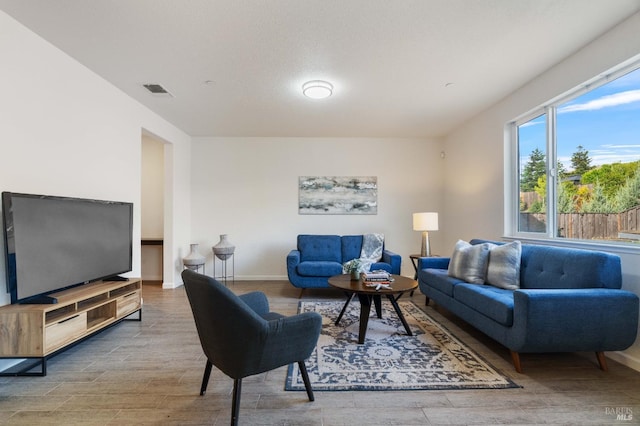 living room with baseboards, wood finished floors, and visible vents