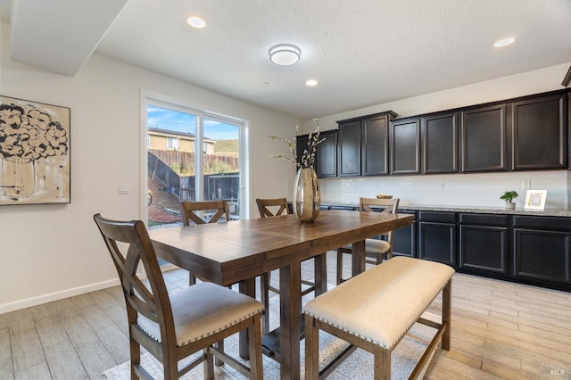 dining space featuring light wood-style floors, baseboards, recessed lighting, and a textured ceiling