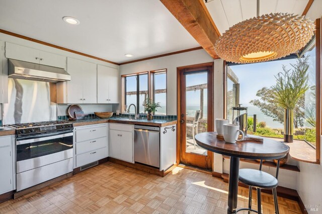 272 Ocean Pkwy, Bolinas, CA 94924 - kitchen with appliances with stainless steel finishes, under cabinet range hood, dark countertops, white cabinets, and ornamental molding