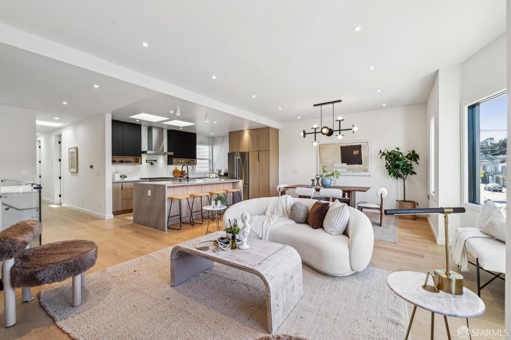 living room featuring light wood-type flooring, a chandelier, and sink