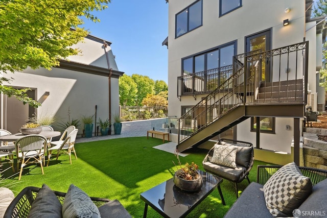 rear view of property with a patio, a balcony, and a lawn