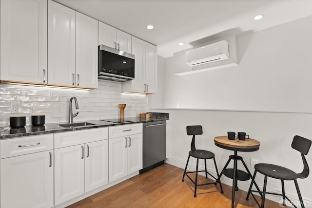 kitchen featuring light wood-type flooring, white cabinetry, sink, and a wall mounted AC